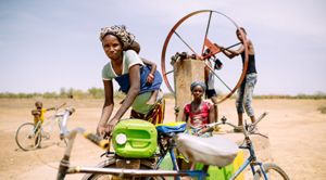 A woman bicycles with her baby to fetch water for her family, Sorobouly village near Boromo, Burkina Faso © Ollivier Girard / Center for International Forestry Research