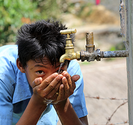 A boy drinks water from a tap stand at his school in Puware Shikhar, Udayapur District, Nepal © Jim Holmes / AusAID