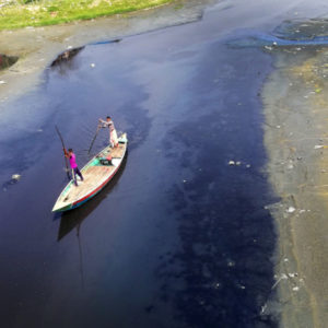 A boat navigating over polluted river water in Dhaka; Credit: Sabrina Zaman/REACH