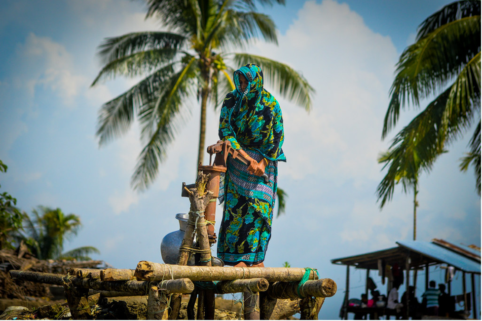 A woman drawing water from a hand pump in Bangladesh